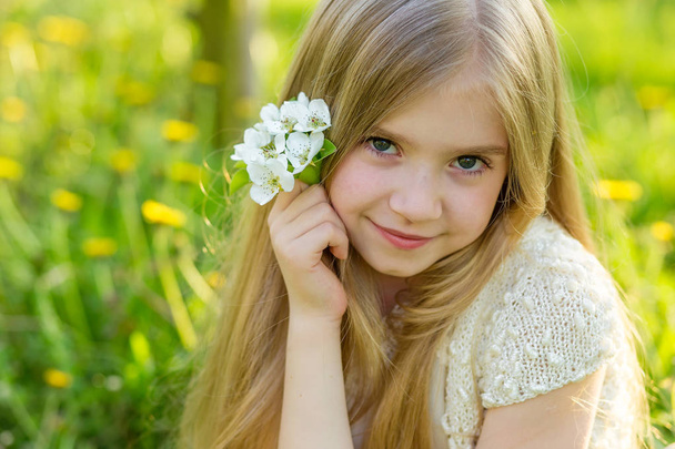 Ένα όμορφο κοριτσάκι που διατρέχει ένας ανθίζοντας κήπος στο s - Φωτογραφία, εικόνα