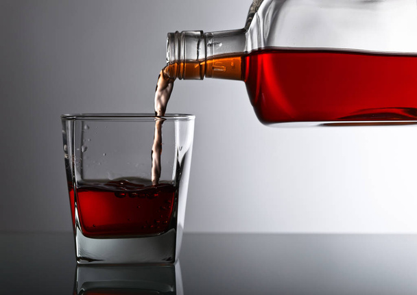 Flasche und Glas Whiskey auf einem Glastisch  - Foto, Bild