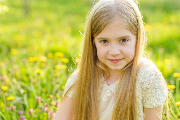 Een mooi klein meisje loopt door een bloeiende tuin in de s - Foto, afbeelding