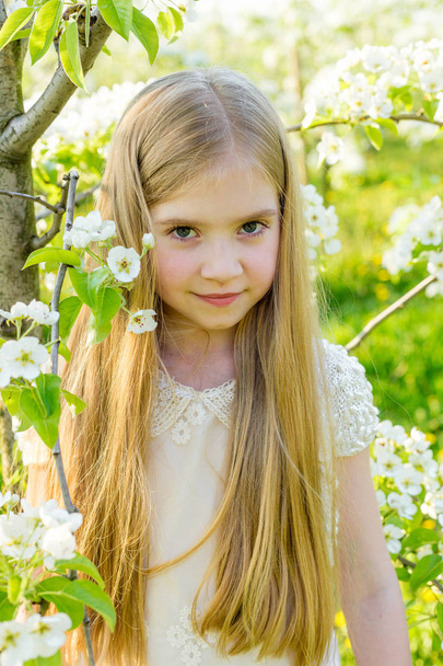 A beautiful little girl runs through a flowering garden in the s - Photo, Image