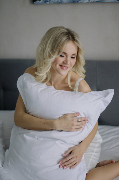 woman sitting on bed with pillow - Zdjęcie, obraz