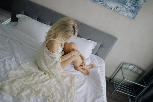 woman sitting on bed sheets - Foto, afbeelding