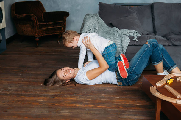 cute mother and her son play on the floor together indoor - Fotó, kép