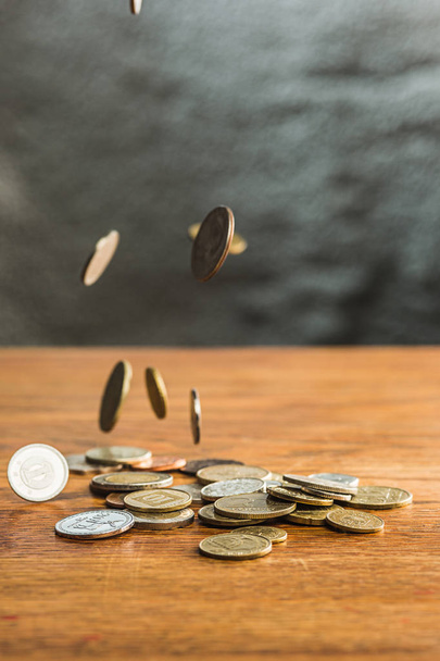 The silver and golden coins and falling coins on wooden table background - 写真・画像