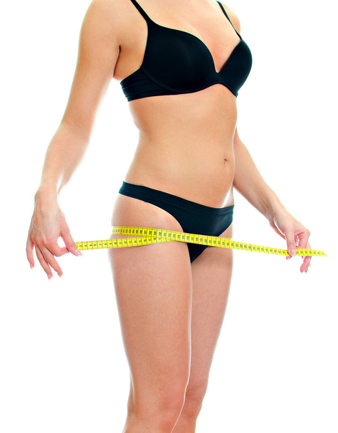 Slim female body with measure tape around hips. Isolated on white - Zdjęcie, obraz