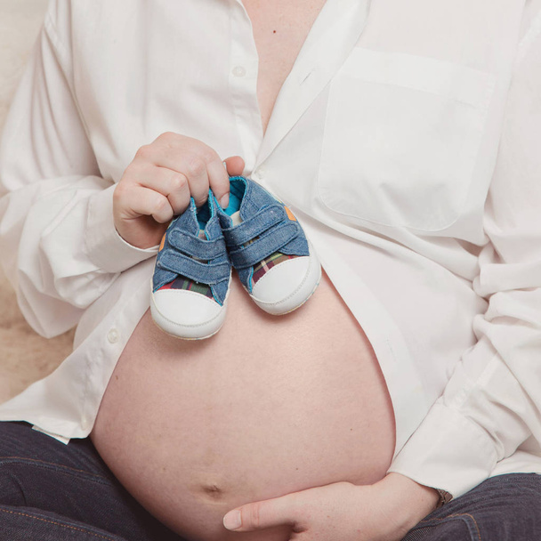 Bebek Ayakkabı tutan hamile kadın  - Fotoğraf, Görsel