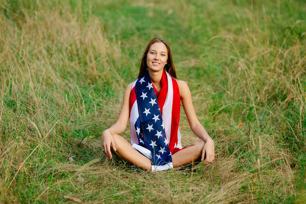 Girl is sitting on the grass with the American flag - Fotó, kép