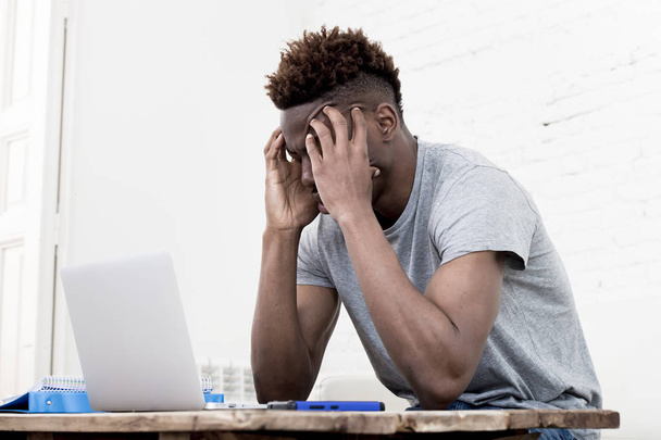 Африканский американец сидит дома и работает с ноутбуком и документами
 - Фото, изображение