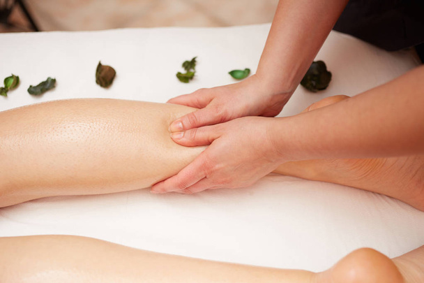 Detail of hands massaging human calf muscle.Therapist applying pressure on female leg - 写真・画像