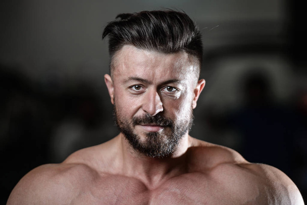 Brutal strong bodybuilder man pumping up muscles and train gym - Photo, Image