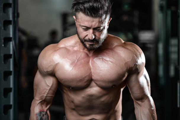 Brutal strong bodybuilder man pumping up muscles and train gym - Foto, Imagen