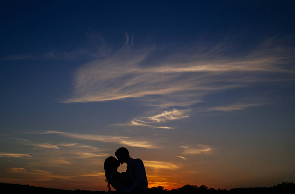 Silhouettes of a loving couple hugging at sunset - Photo, Image