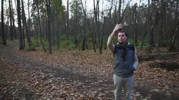 Séta az őszi erdőben felnőtt ember. Turisztikai teszi fényképek egy új helyen. - Felvétel, videó