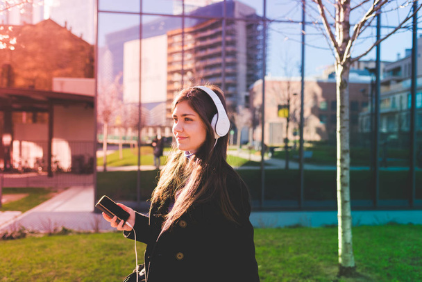 γυναίκα ακούτε μουσική με ακουστικά και το έξυπνο κινητό τηλέφωνο  - Φωτογραφία, εικόνα
