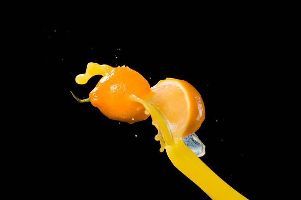 two halves of lemon and splash of juice isolated on black backgr - Foto, afbeelding