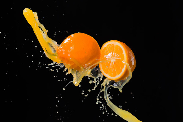 two halves of lemon and splash of juice isolated on black backgr - Fotografie, Obrázek