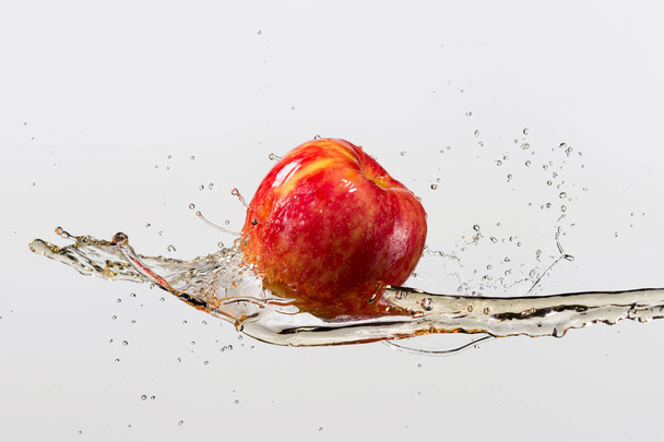red apple and splash of juice in white background - Фото, изображение