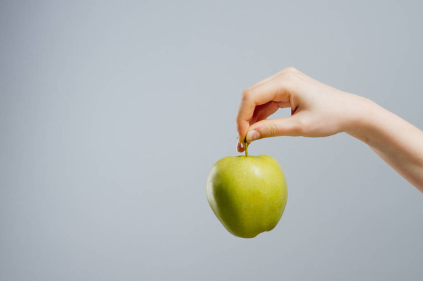 Γυναίκα σε δίαιτα με ένα μήλο στο χέρι ενάντια σε γκρίζο φόντο - Φωτογραφία, εικόνα