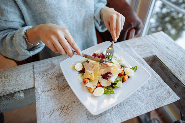 Женщина ест восхитительный салат Цезарь в ресторане. Крупный план
 - Фото, изображение