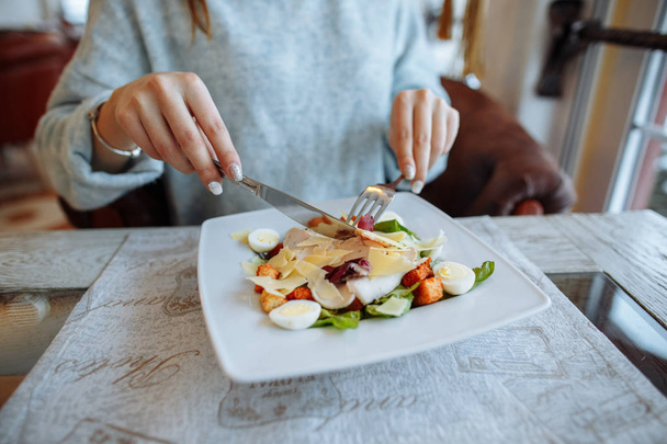 Женщина ест вкусный салат Цезарь на столе в ресторане
 - Фото, изображение
