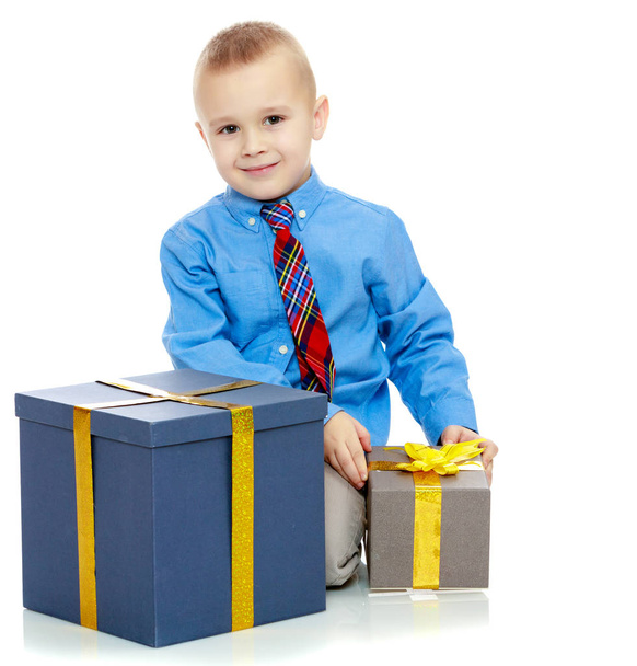 Le petit garçon regarde la boîte avec les cadeaux
 - Photo, image