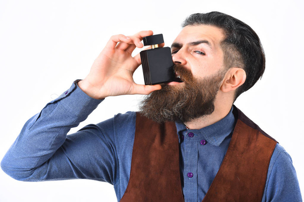 szakállas férfi kezében parfüm komoly arccal - Fotó, kép