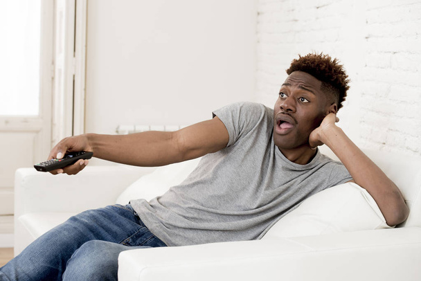 attractive black african american man sitting at home sofa couch watching television - Photo, Image