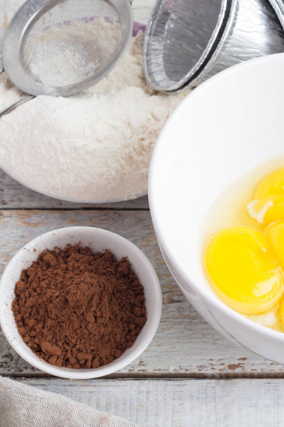 Kom met meel, eieren, cacao en melk  - Foto, afbeelding