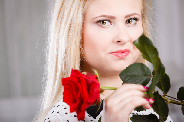 woman holding red rose near face looking melancholic - 写真・画像