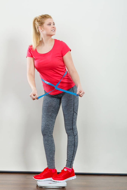 Woman wearing sportswear standing on weight machine - Photo, image