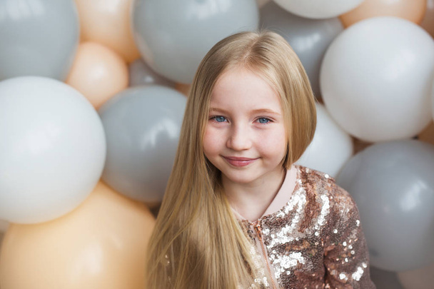 Portrait of pretty little blonde girl on a balloons background - Fotó, kép