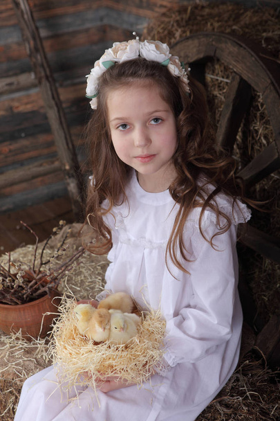 Girl in a wreath holding a nest with live chickens - Fotoğraf, Görsel