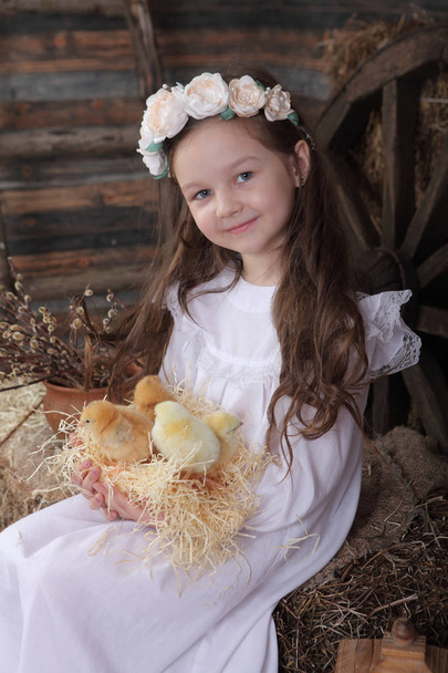 Girl in a wreath holding a nest with live chickens - Fotoğraf, Görsel