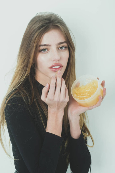 Pretty girl putting gel or balm on sexy lips - Фото, изображение