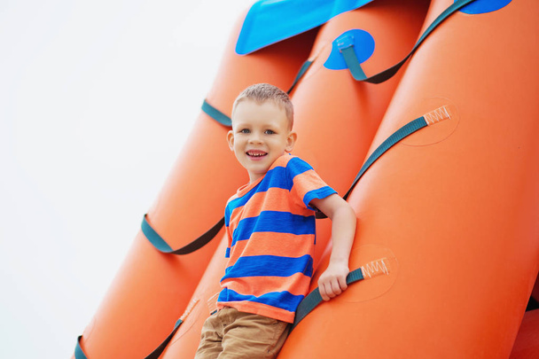 Petit garçon jouant sur une aire de jeux gonflable sur la plage
 - Photo, image