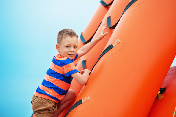 boy playing on an inflatable playground on the beach on a summer - Foto, Imagen