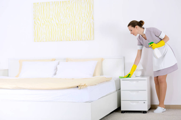 Chambermaid cleaning bedside table  - Foto, imagen