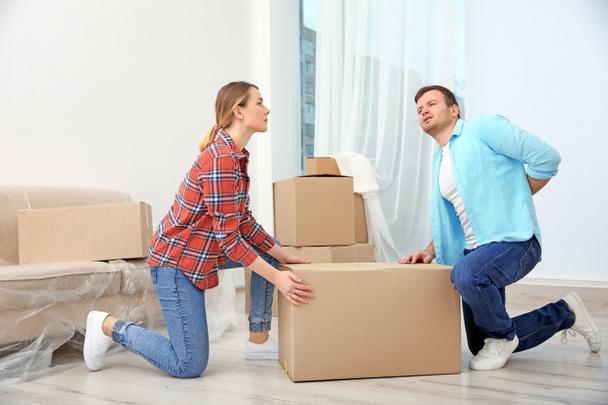 Man suffering from ache while moving box in room - 写真・画像