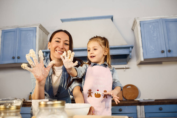 Mom and daughter showing them hands in dough - Φωτογραφία, εικόνα