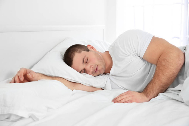 Fiatal, vonzó férfi alszik az ágyban otthon - Fotó, kép