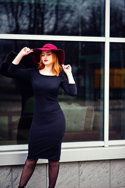 Portrait of fashion red haired girl on red hat and black dress w - Foto, afbeelding
