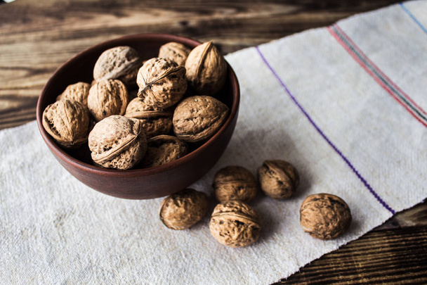 bowl with walnuts on wooden background - Foto, afbeelding