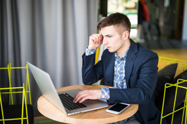 Giovane uomo teso che lavora sul computer portatile al tavolo del caffè e pensando
 - Foto, immagini