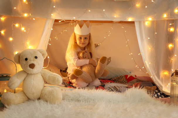 Cute little girl sitting in hovel with cuddly toy - Foto, Bild