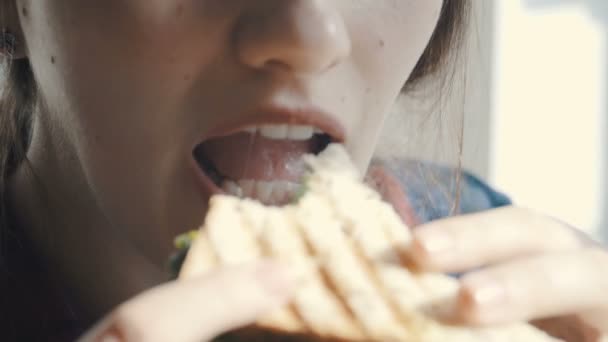 Close-up of a girl enjoying a fresh hamburger - Filmati, video