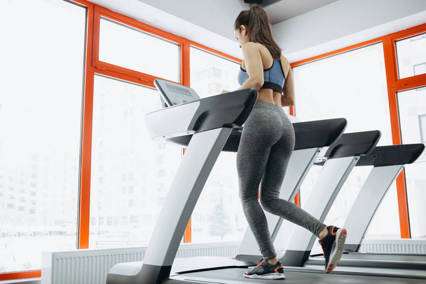 Young fit pretty woman doing exercises on the treadmill - Foto, Imagen