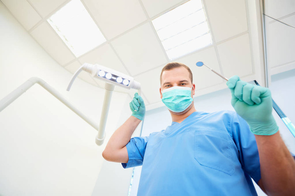 Bottom view. Dentist man with a tool in his hand in  dental offi - Foto, Imagen