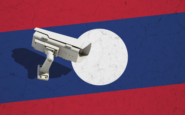 Security camera on wall with painted Laos flag background. Concept political relations with neighbors - Photo, Image
