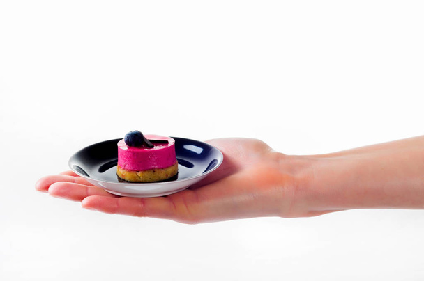 Womans hand holding small dessert cake on delicate set plate - Fotoğraf, Görsel