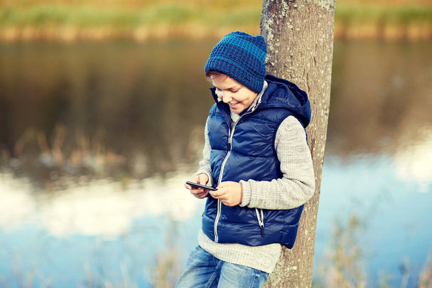 happy boy playing game on smartphone outdoors - Fotoğraf, Görsel